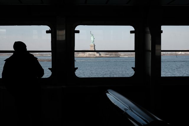 A man looks out at The Statue of Liberty in New York Harbor from the Staten Island Ferry.